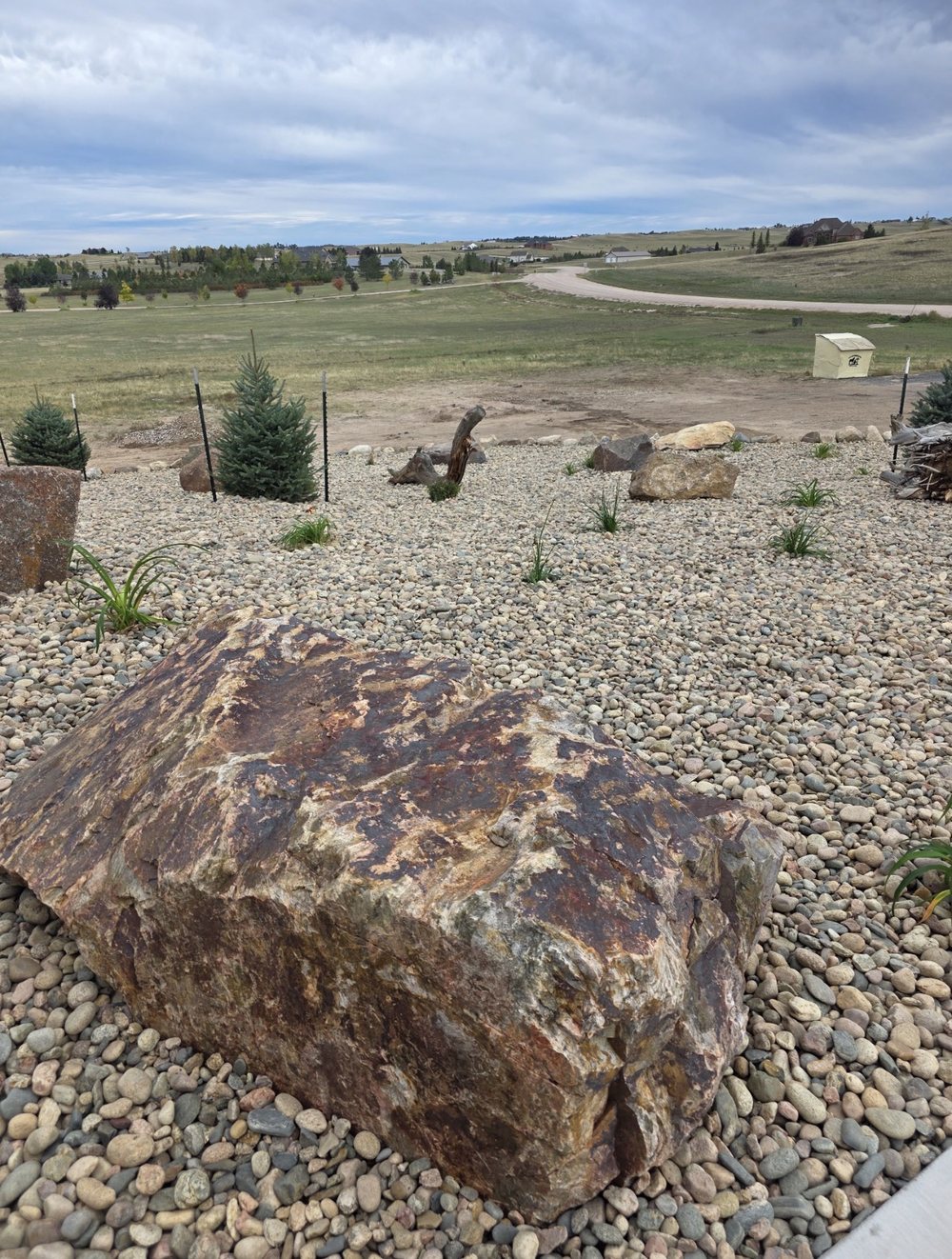 Large natural stone boulder placed in a river rock landscape bed, Cheyenne, Wyoming
